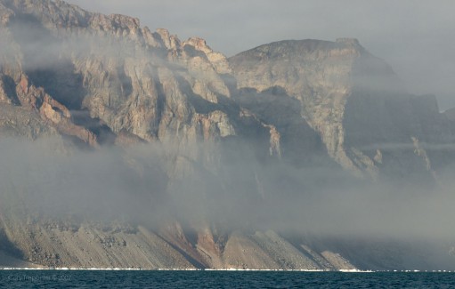 Mountain forms through the fog.