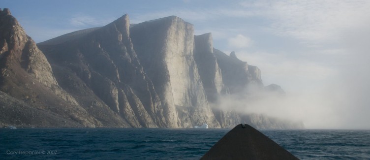 Through the mist a massive, sheer rock face emerges.