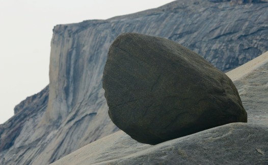 A boulder perched quietly on the slope of rock.
