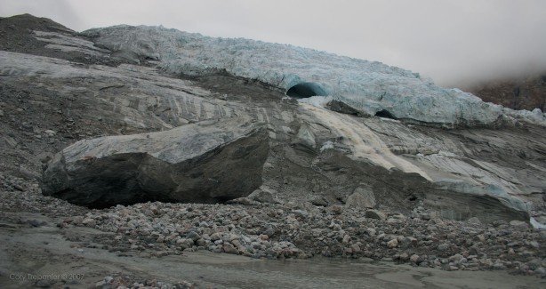 A river pours out of the tunnel in the glacier.